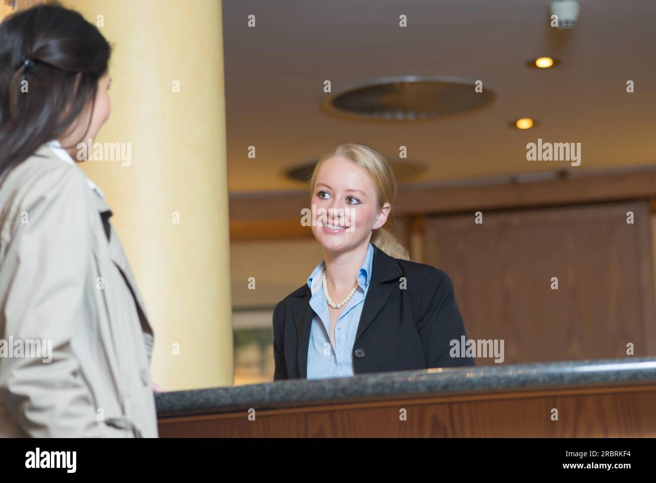 Beautiful stylish blond hotel receptionist standing behind the service