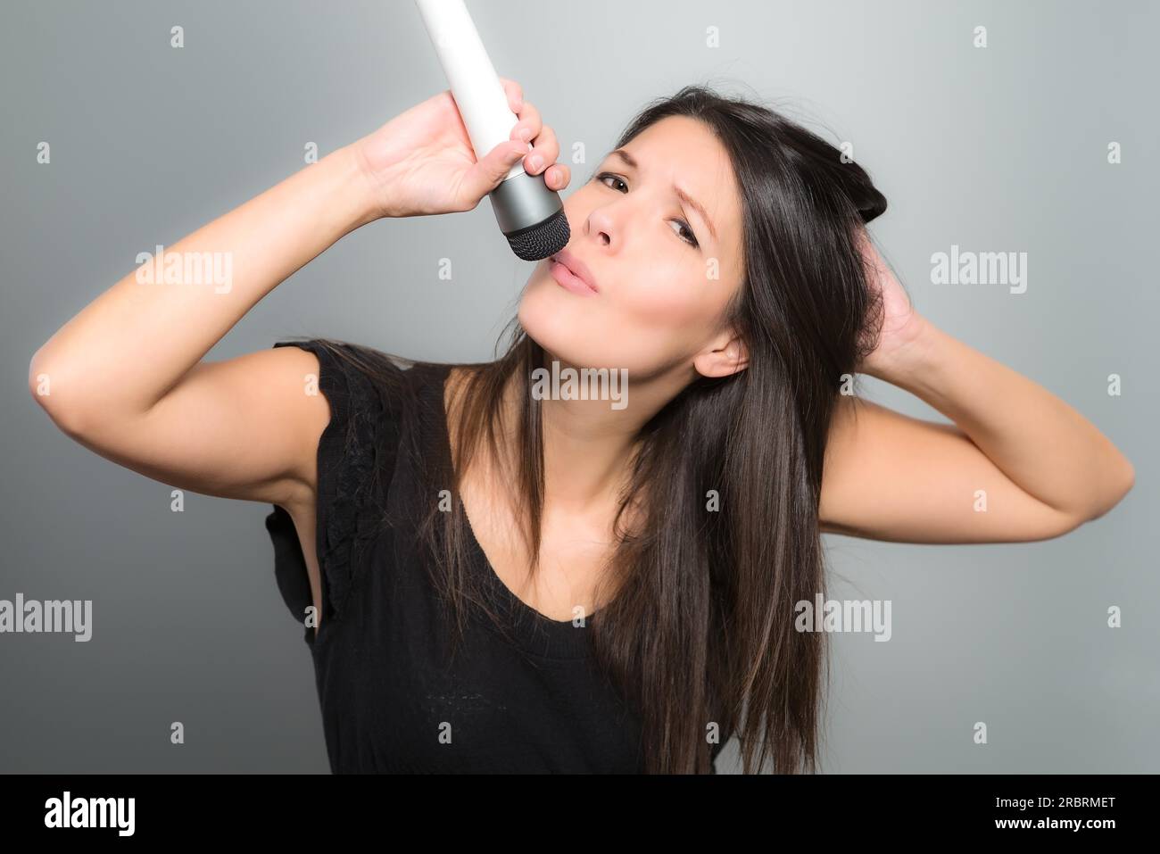 Emotional young woman singing her heart out into a microphone as she