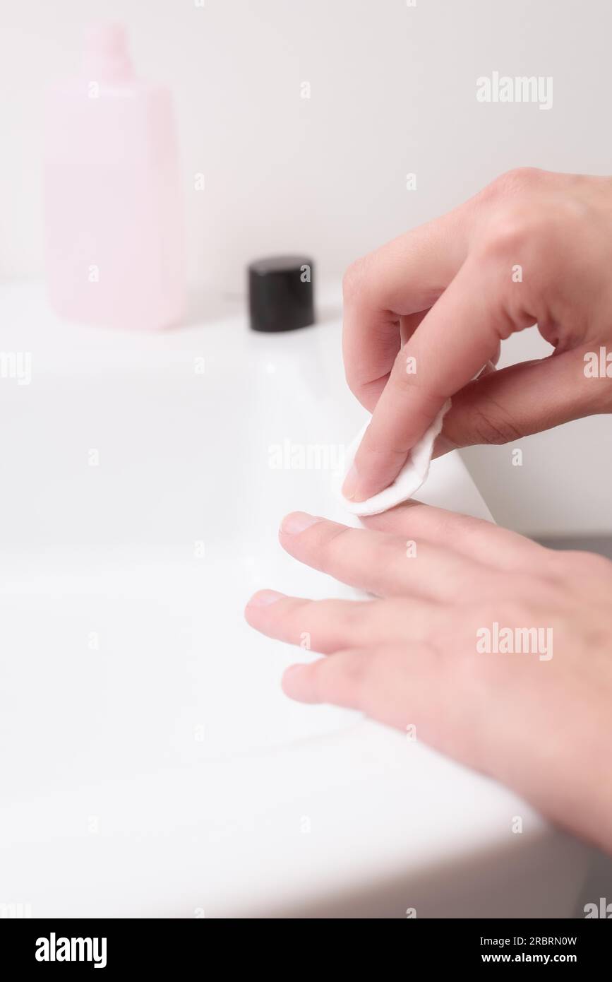 Woman removing nail varnish with acetone on a small cotton pad on the ...