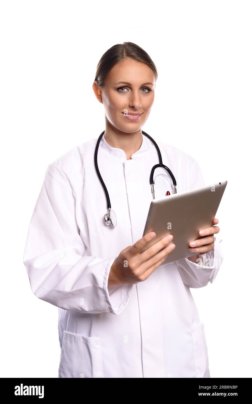 Attractive female nurse or doctor in a white gown standing consulting a tablet computer reading the information with a friendly expression, isolated Stock Photo