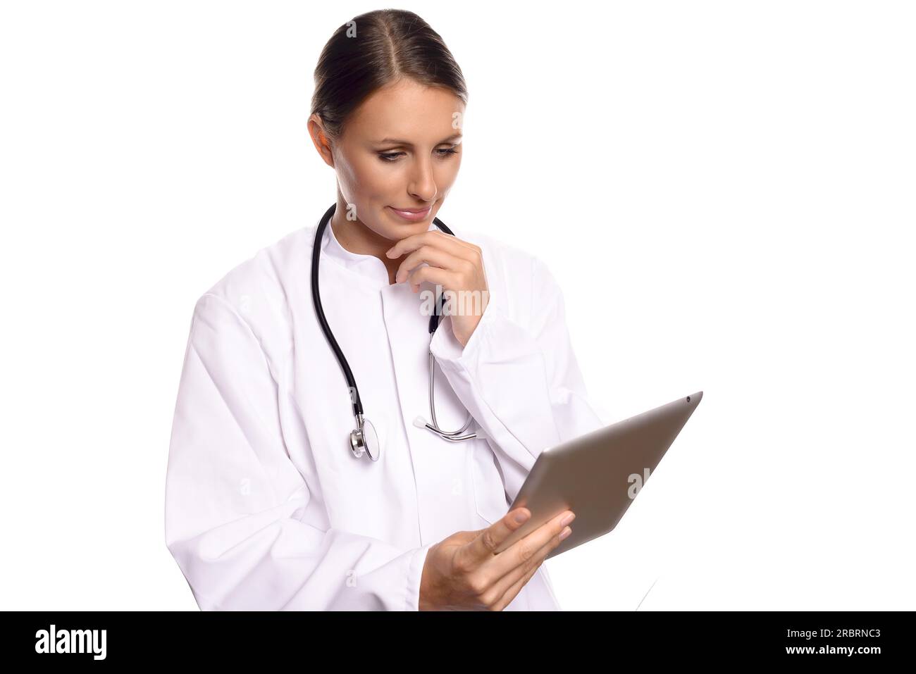 Attractive female nurse or doctor in a white gown standing consulting a tablet computer reading the information with a serious expression, isolated Stock Photo