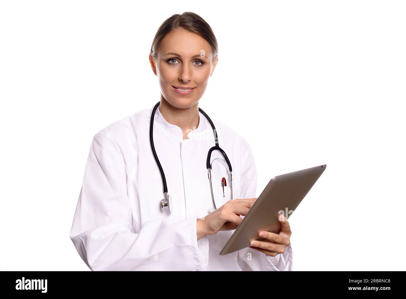 Attractive female nurse or doctor in a white gown standing consulting a tablet computer reading the information with a friendly expression, isolated Stock Photo