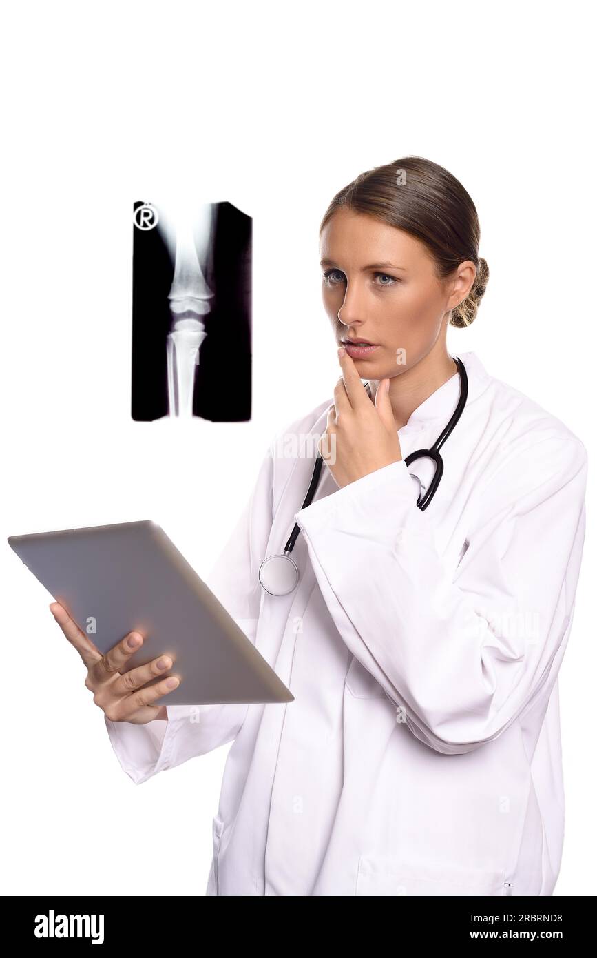 Attractive female nurse or doctor in a white gown standing consulting a tablet computer reading the information with a serious expression, isolated Stock Photo