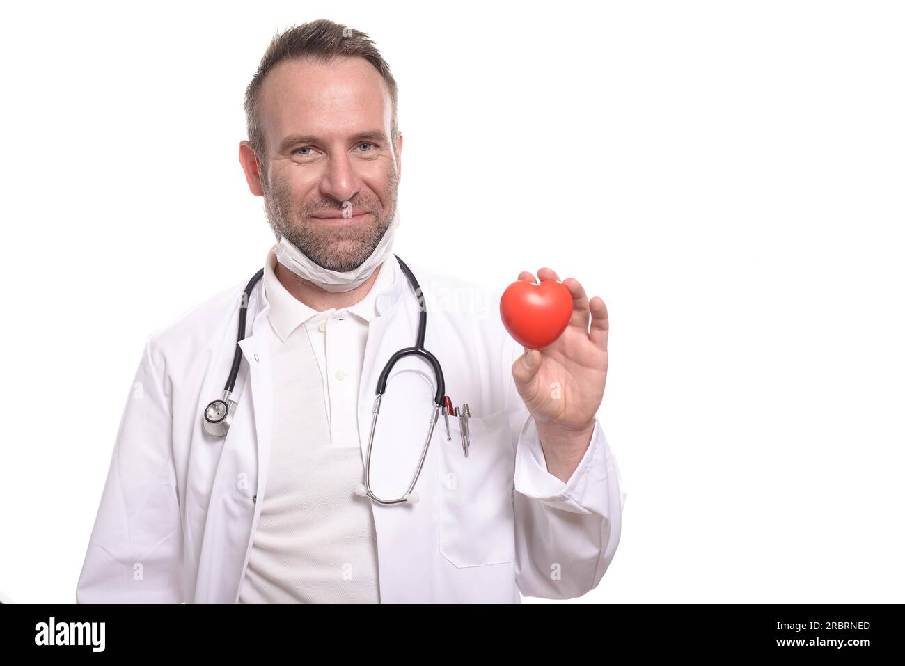 Smiling doctor or in a mask, stethoscope and white lab coat holding a bright red heart in his hand conceptual of a health care, isolated on white Stock Photo