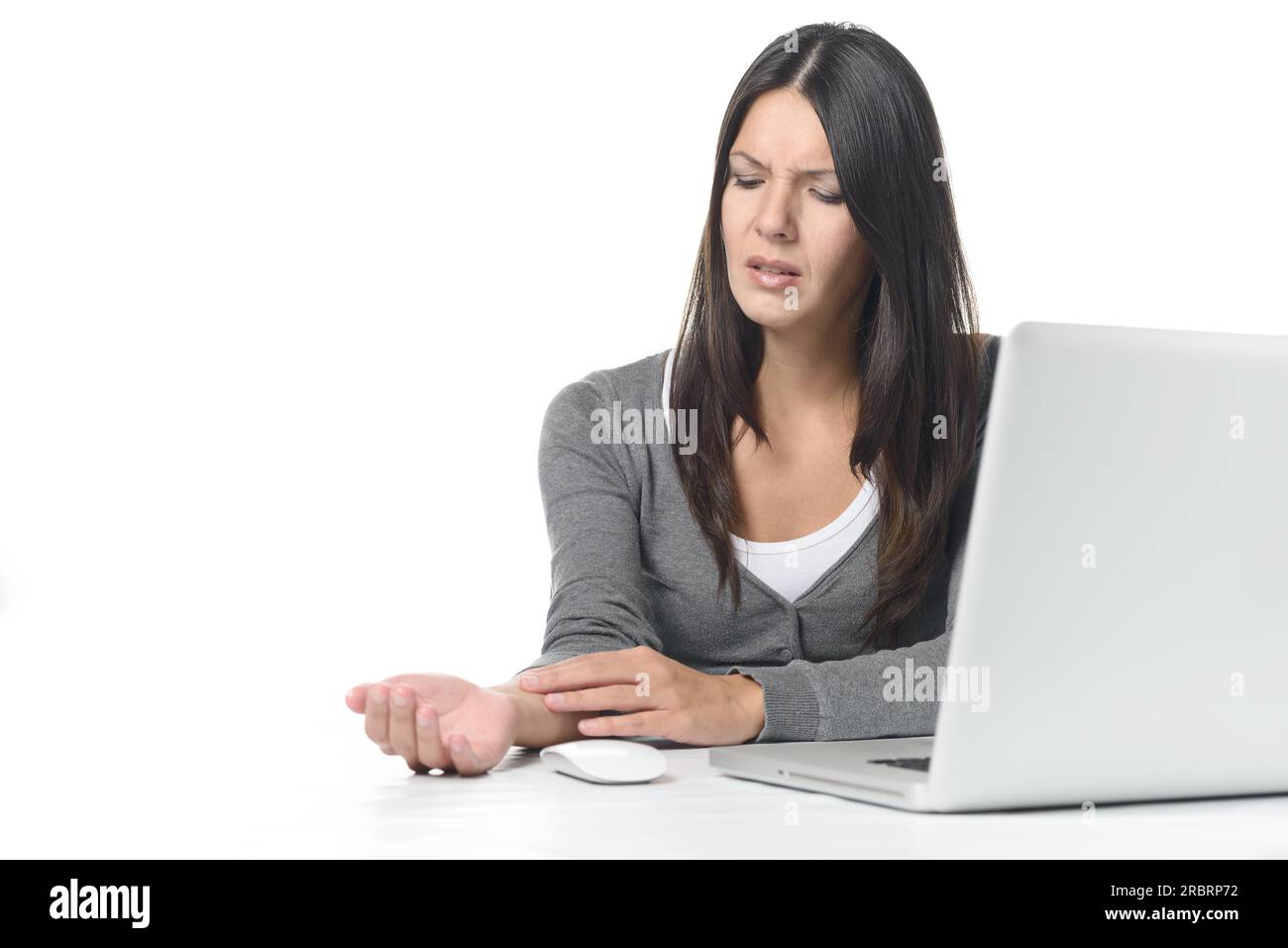 Young businesswoman rubbing and massaging her wrist to relieve cramps after using a computer mouse for too long at a stretch, on white Stock Photo