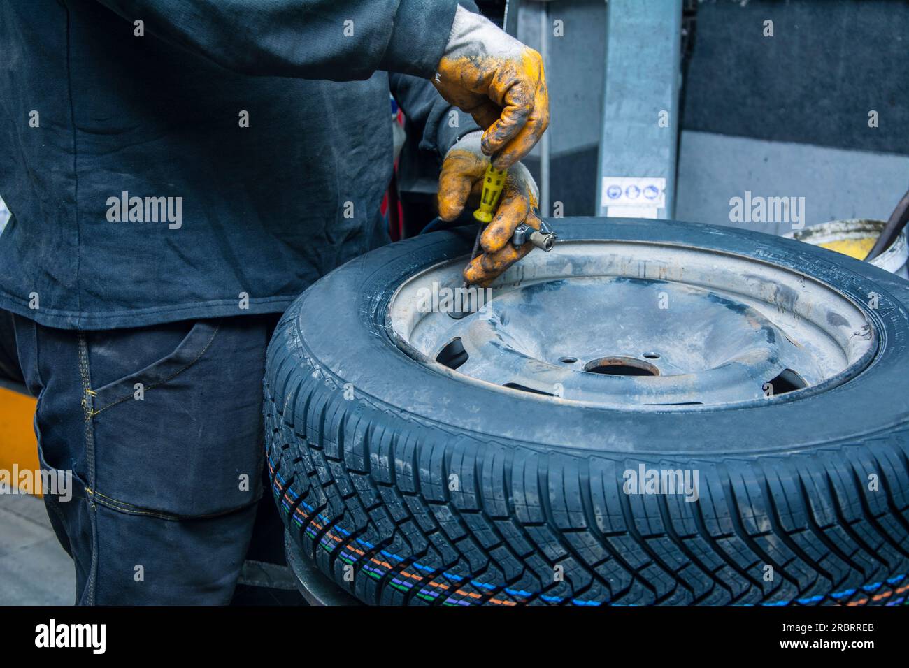 Unrecognizable service man adjusting the valve of the new tire Stock Photo