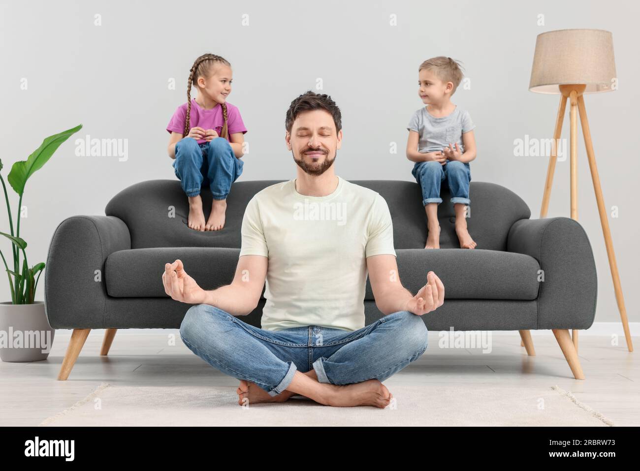 Father meditating while his children sitting on sofa at home Stock Photo
