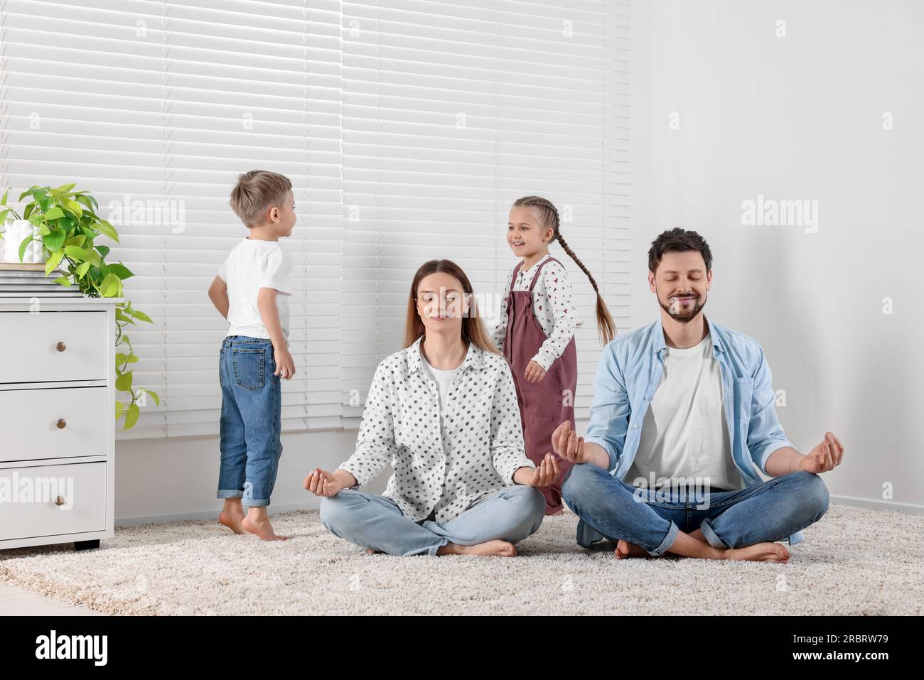 Parents meditating while children distracting them at home Stock Photo