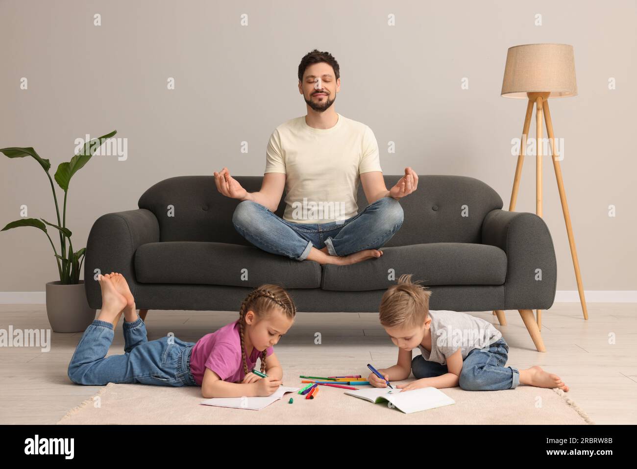 Father meditating while his children painting at home Stock Photo
