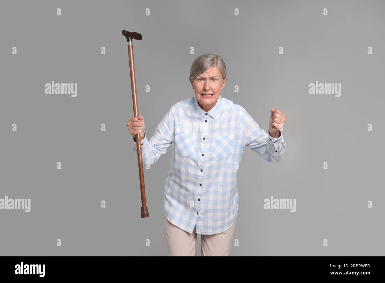 Angry senior woman with walking cane on gray background Stock Photo - Alamy