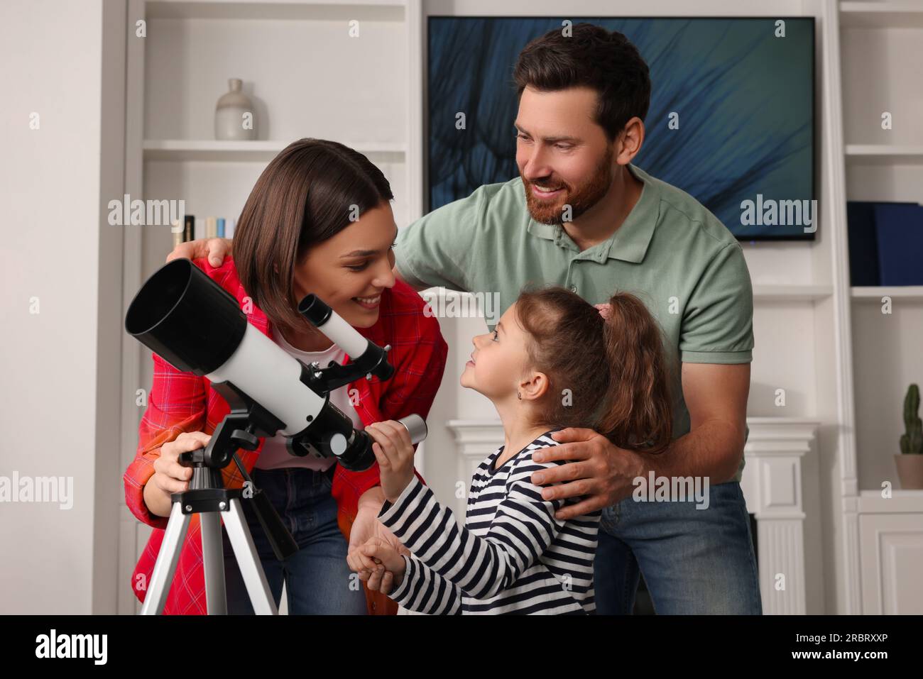 Happy family using telescope to look at stars in room Stock Photo Alamy