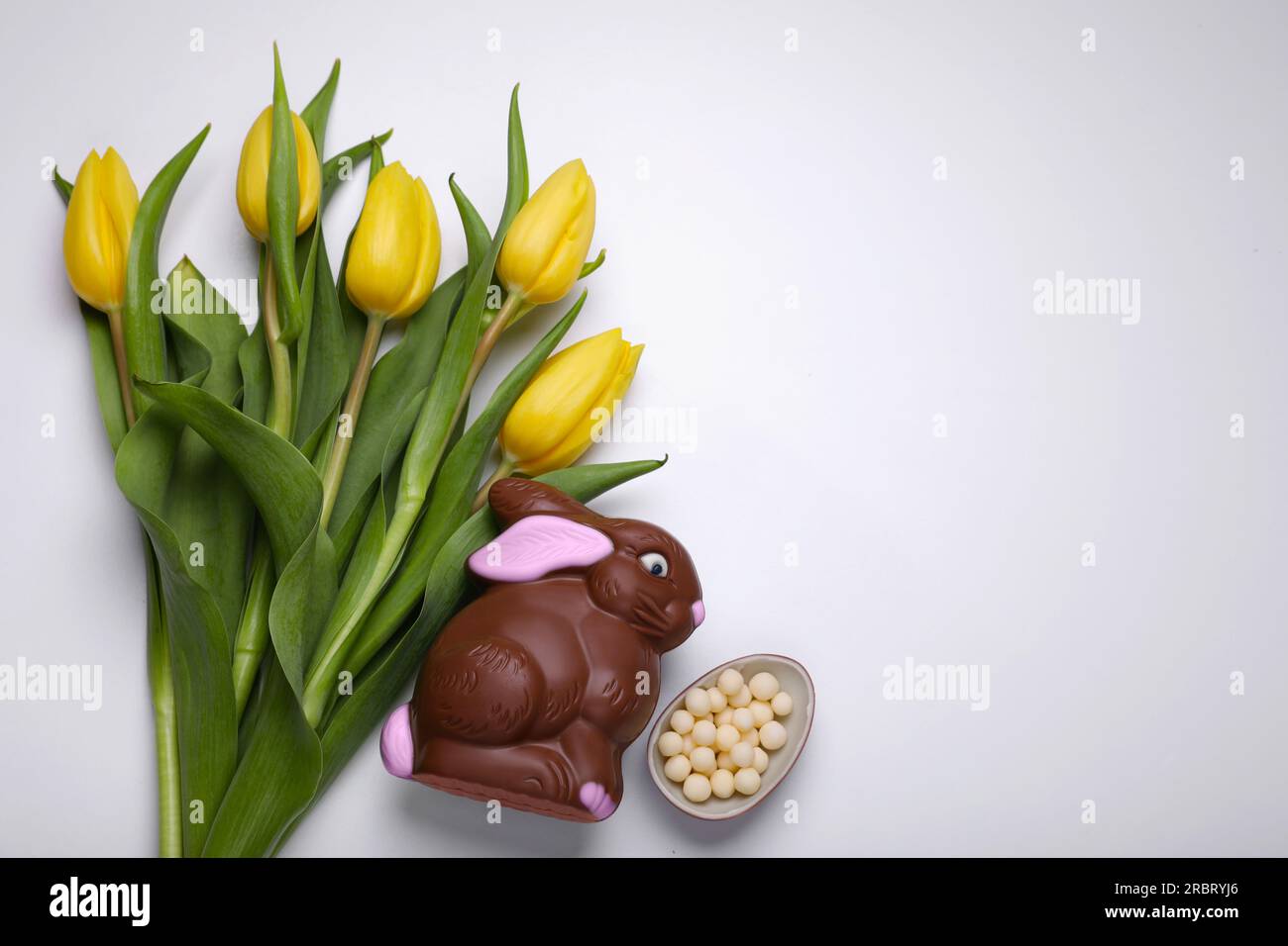 Flat lay composition with chocolate bunny and beautiful tulips on white ...
