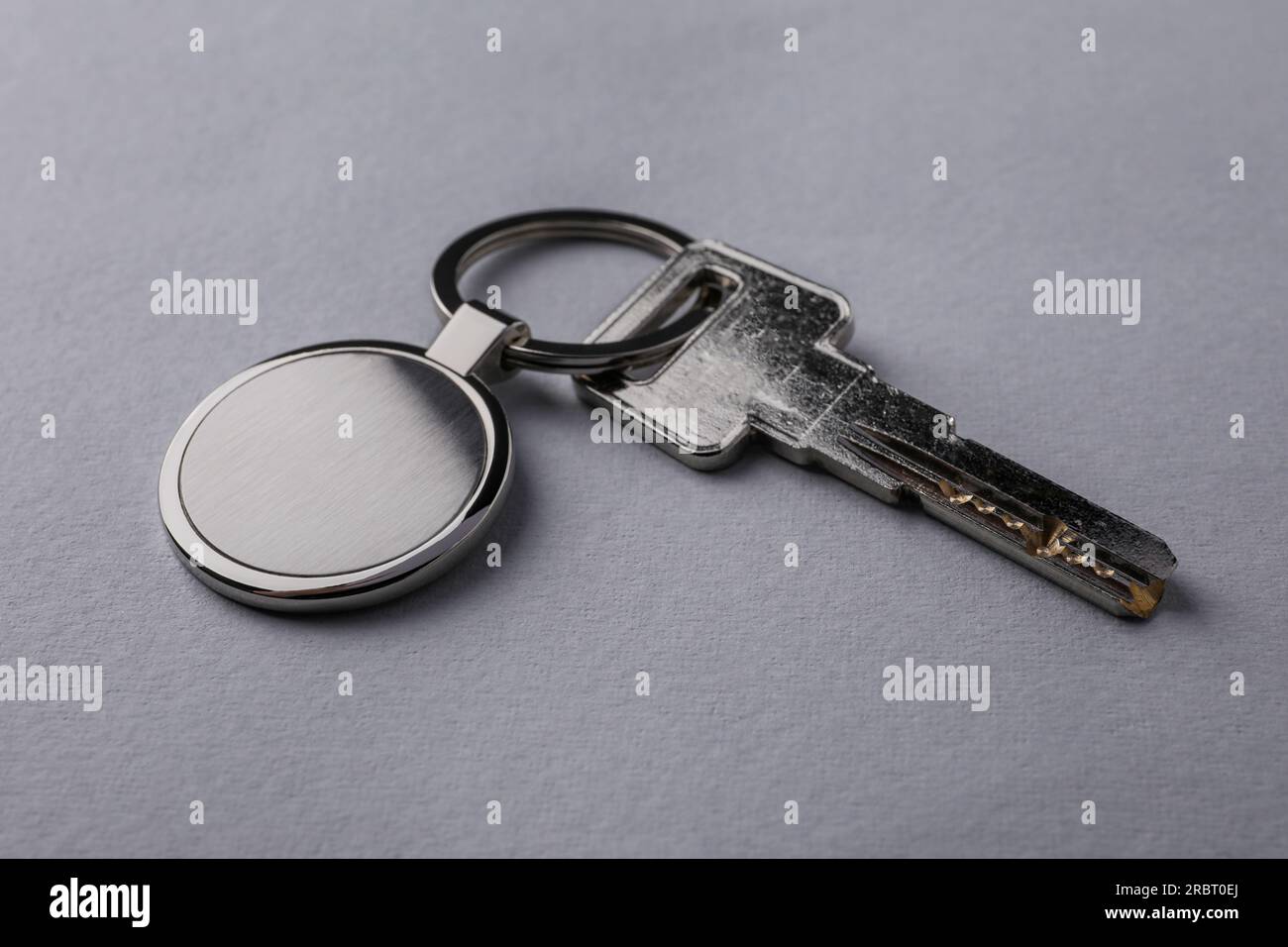 Key with metallic keychain on light grey background, closeup Stock Photo