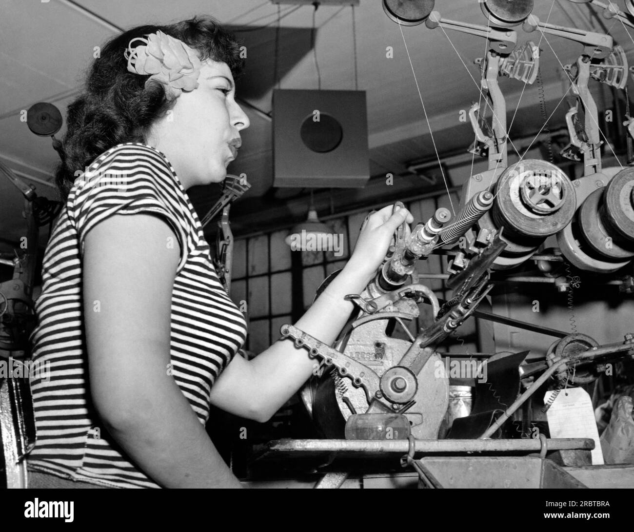 Camden, New Jersey:   January, 1945            Former show girl Kaye Grimm now helps with the home front war effort at the RCA Victor plant in Camden, NJ. She whistles while she works to music from the overhead speaker. Stock Photo