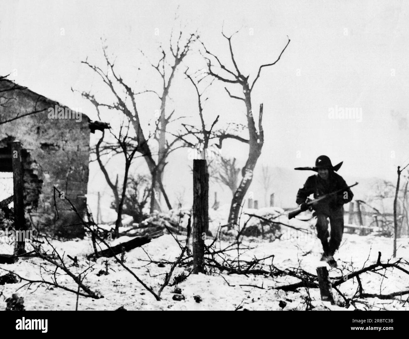 Mettingen, Germany, January 30, 1945 94th Division infantryman dashes for cover through a shell-torn orchard outside Mettingen. Stock Photo