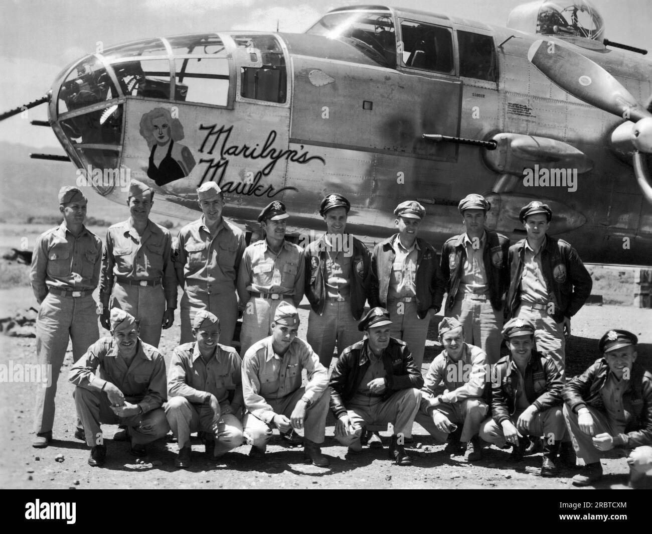 SE Asia:  c. 1943 The crew of a B-25 bomber named the 'Marilyn's Mauler' poses beside it somewhere in the Pacific theater during WWII. Stock Photo