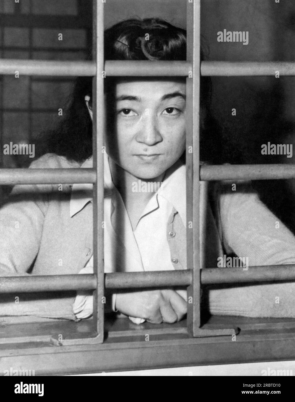 Yokohama, Japan, October 28, 1945 Iva Toguri, known as "Tokyo Rose" of the Japanese propaganda "Zero Hour" broadcasts which were beamed at U. S. troops in the Pacific during the war, as she looks through the bars of her cell. Born in Los Angeles in 1916, she is awaiting trial for treason against the United States. Stock Photo