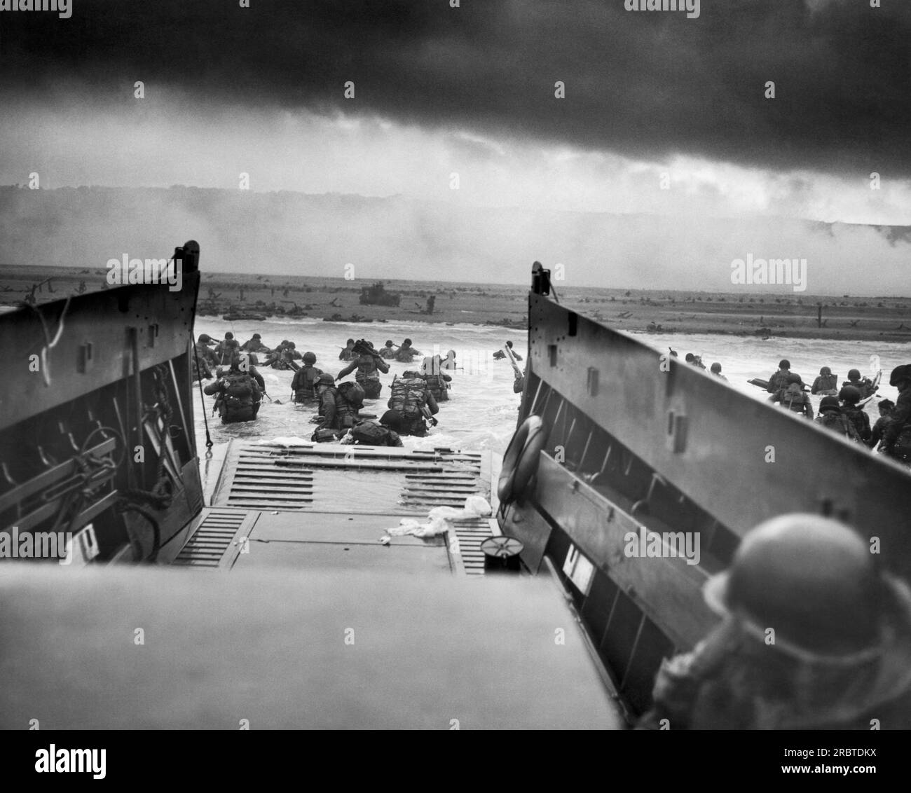 Normandy, France:   June 6, 1944  A Landing Craft Vehicle, Personnel, (LCVP), the USS Samuel Chase, disembarks troops of Company E, 16th Infantry, 1st Infantry Division (the Big Red One) onto the Fox Green section of Omaha Beach on the morning of D-Day. The American soldiers encountered withering machine gun fire from the German 352nd Division while wading ashore. During the initial landing, two-thirds of Company E became casualties. Photo by Robert Sargent, U.S. Coast Guard. Stock Photo