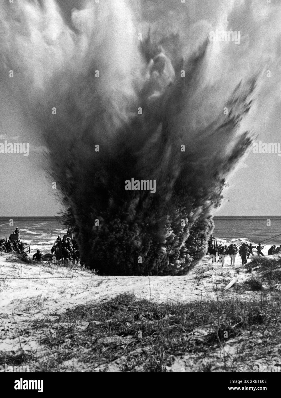 United States,  May 13, 1943 US Coast Guardsmen parcticing invasion tactics while a land mine explosion adds realness to the maneuver. Stock Photo