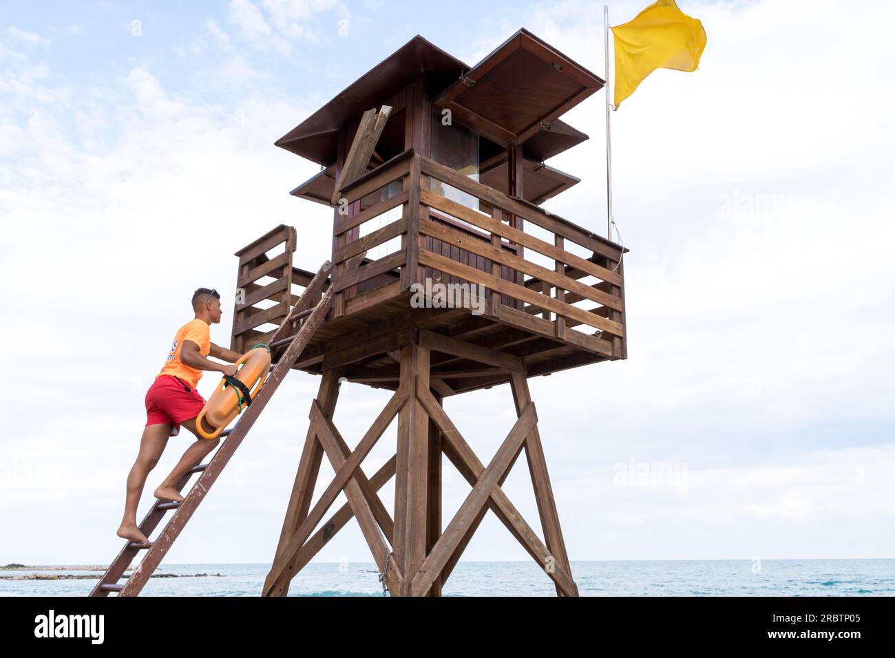 Rescuer with a float climbing a control tower next to the sea Stock
