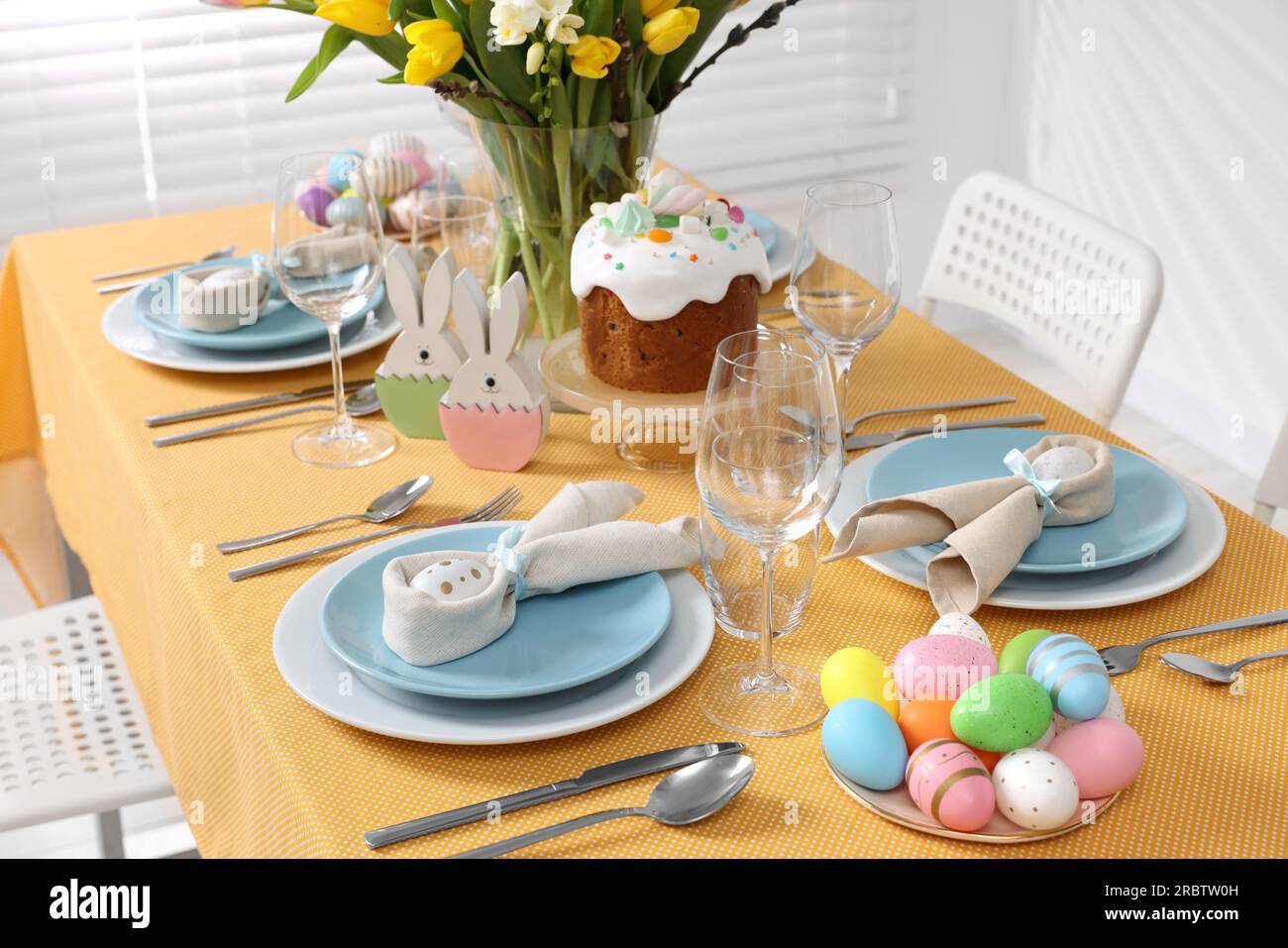 Festive table setting with painted eggs, traditional Easter cake and vase of tulips Stock Photo