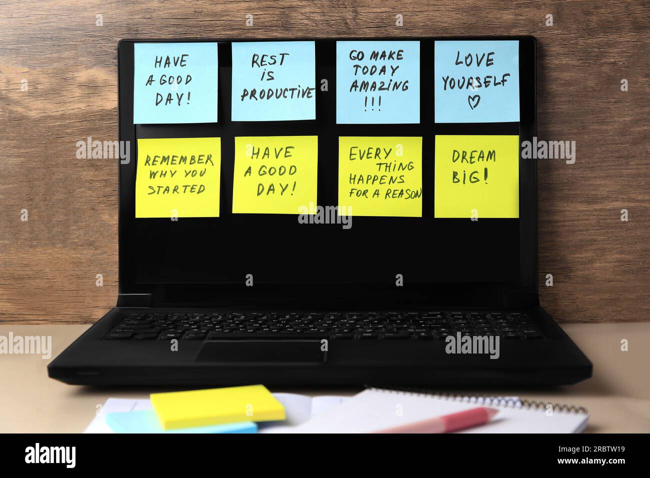 Laptop with paper notes of life-affirming phrases on beige desk indoors Stock Photo