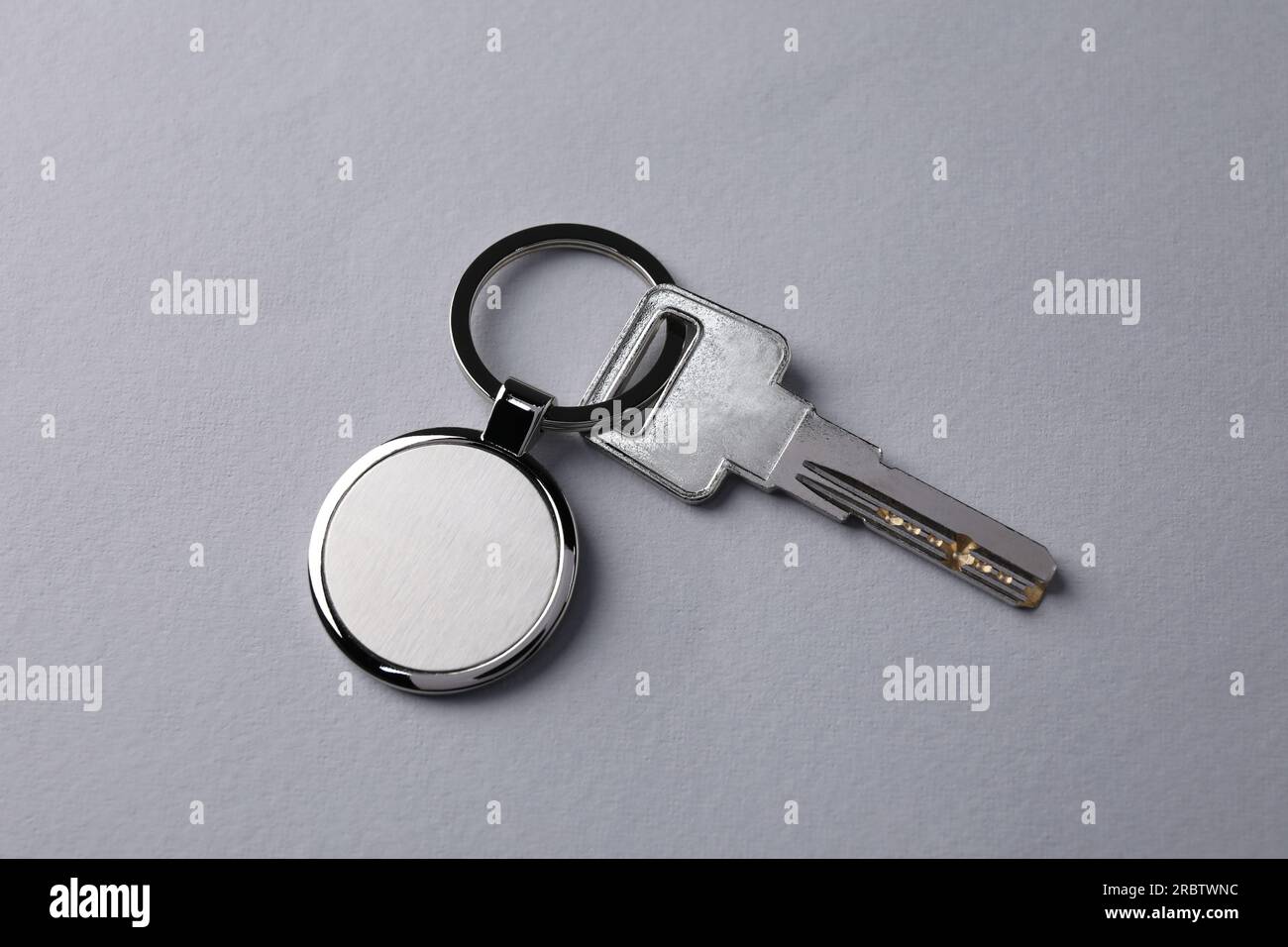 Key with metallic keychain on light grey background, top view Stock Photo