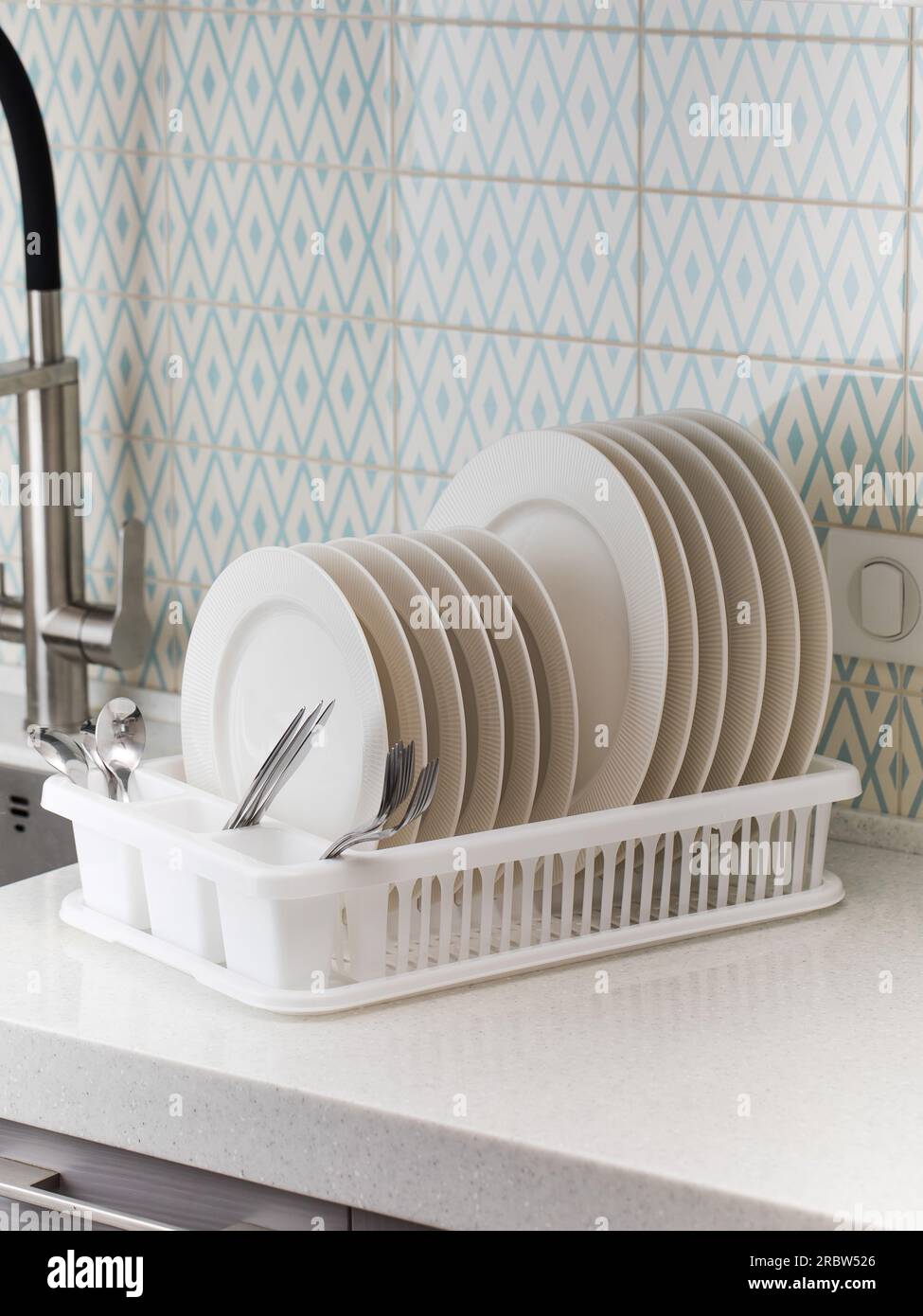 https://c8.alamy.com/comp/2RBW526/a-plastic-dish-drying-rack-stands-at-the-sink-in-the-kitchen-with-clean-dishes-inside-2RBW526.jpg