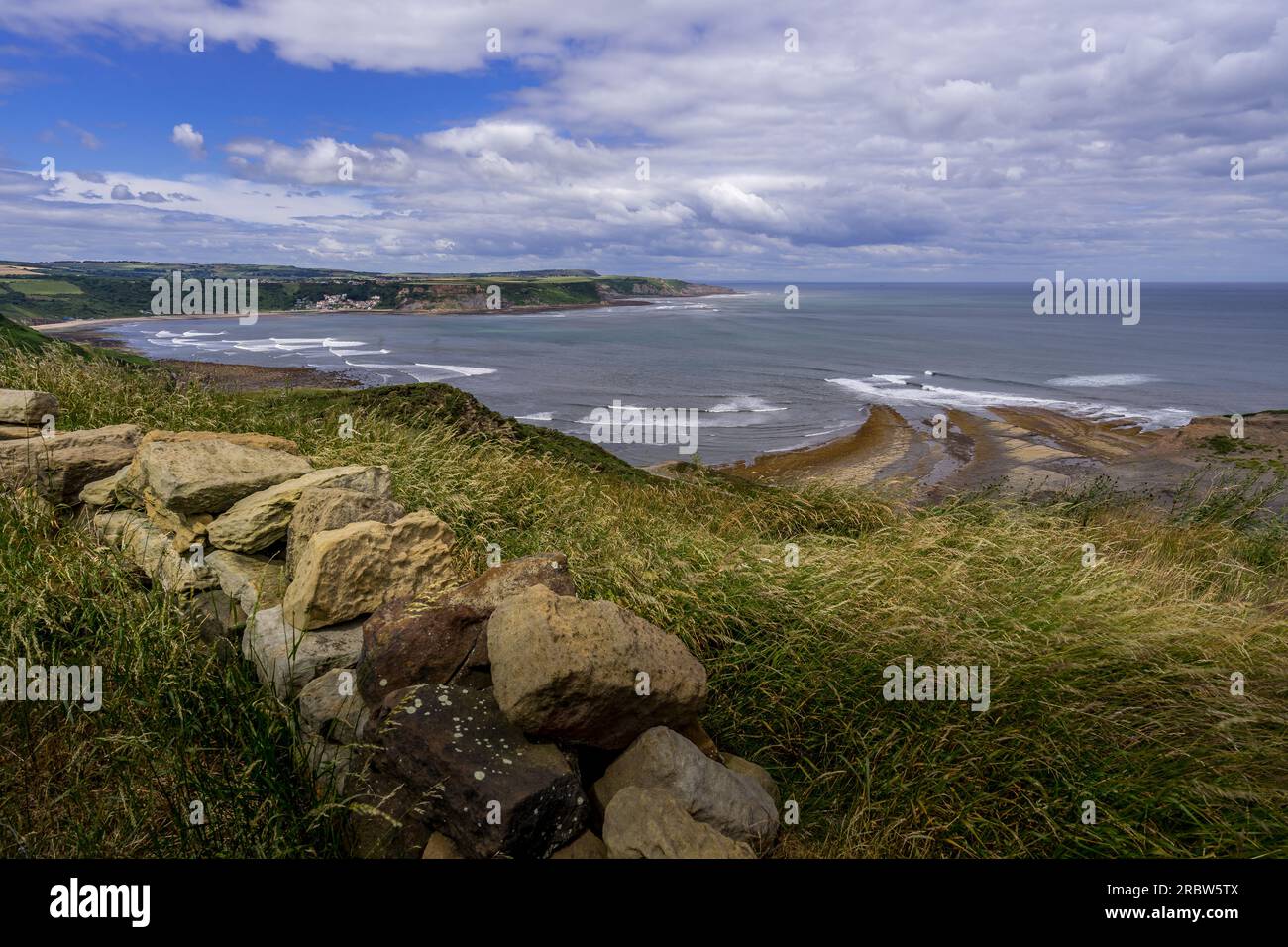 View from the Cleveland Way. This clifftop view is seen as you walk north approaching Kettleness, at the other side of the bay is the seaside village Stock Photo