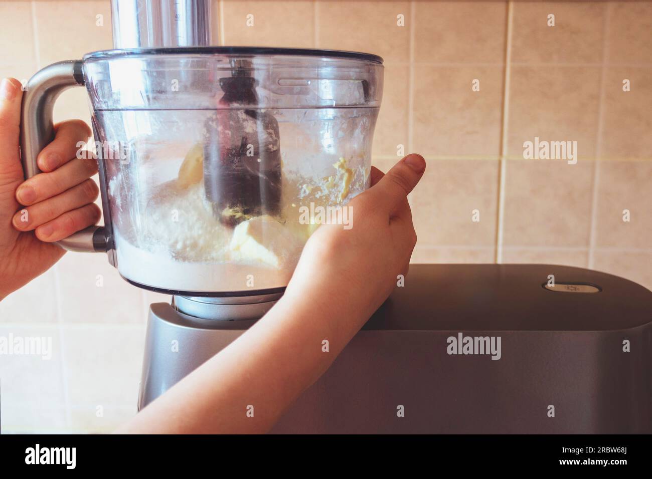 hands hold a bowl of the food processor. Preparation of shortcake dough