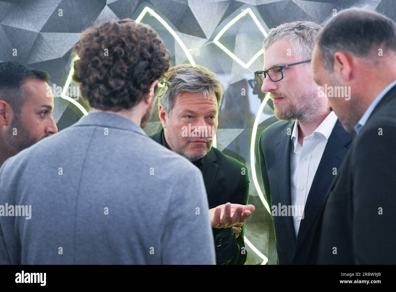 Heidelberg, Germany. 11th July, 2023. Robert Habeck (M, Bündnis 90/Die Grünen), Federal Minister of Economics and Climate Protection, talks to employees during his visit to Aleph Alpha GmbH in Heidelberg, a developer of AI language models. To Habeck's right is Samuel Weinbach, a co-founder of Aleph Alpha. Credit: Bernd Weißbrod/dpa/Alamy Live News Stock Photo