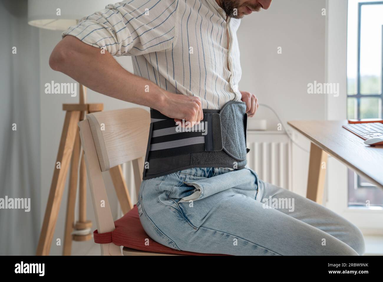 Man wearing back brace at home Stock Photo