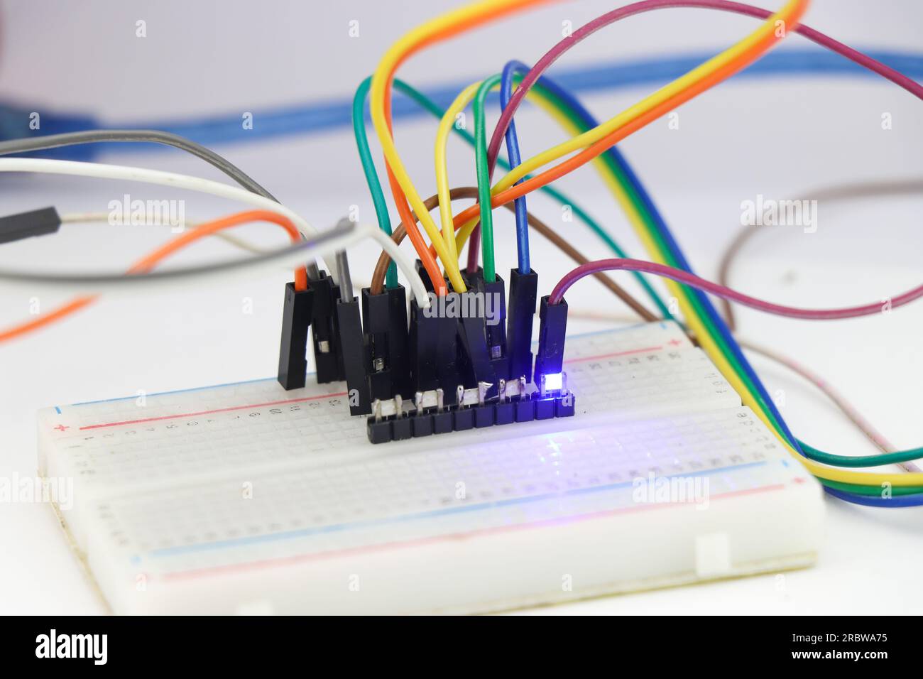 Group of SMD led on a breadboard connected with jumper wires and emitting a blue light Stock Photo