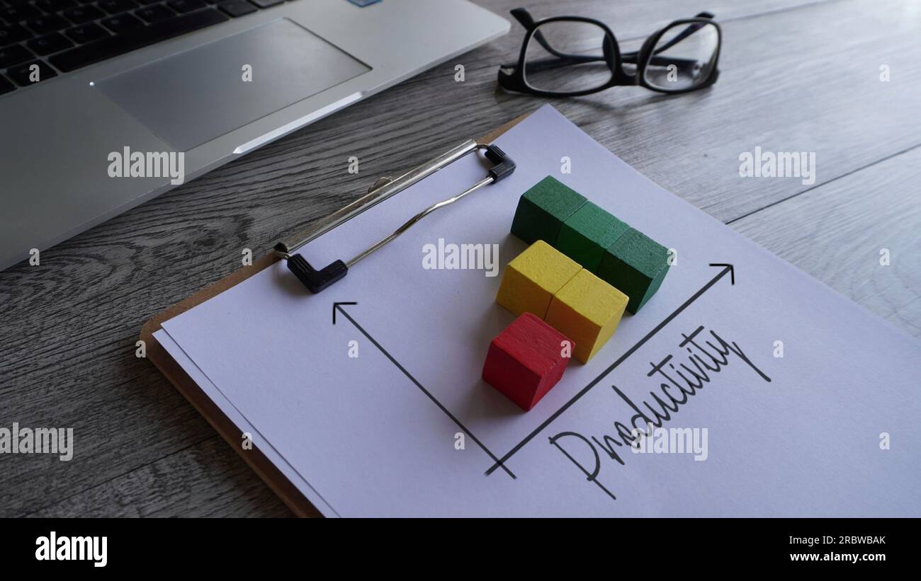 Upward graph with text PRODUCTIVITY on table with glasses and laptop. Business concept Stock Photo