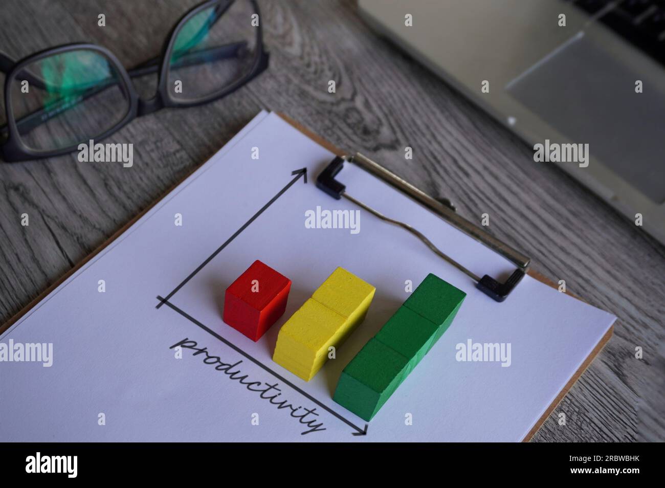 Upward graph with text PRODUCTIVITY on table with glasses and laptop. Business concept Stock Photo