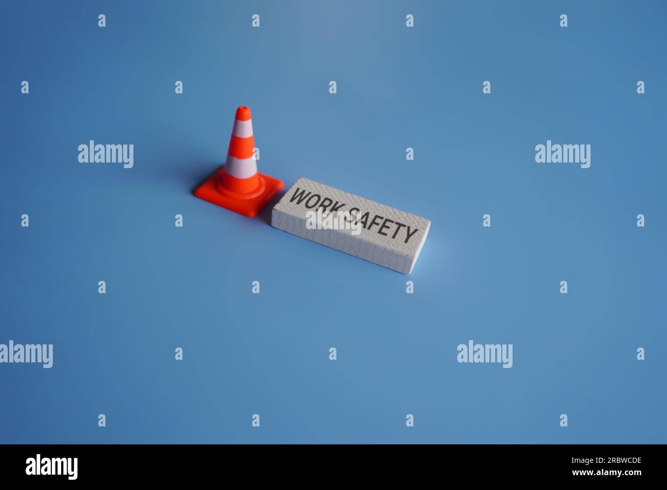 Traffic safety cone and text WORK SAFETY on blue background. Safety at workplace concept Stock Photo