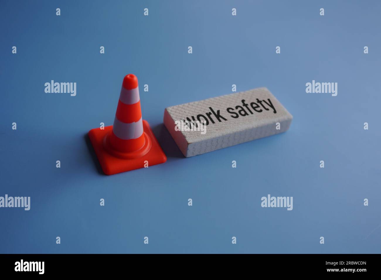 Traffic safety cone and text WORK SAFETY on blue background. Safety at workplace concept Stock Photo