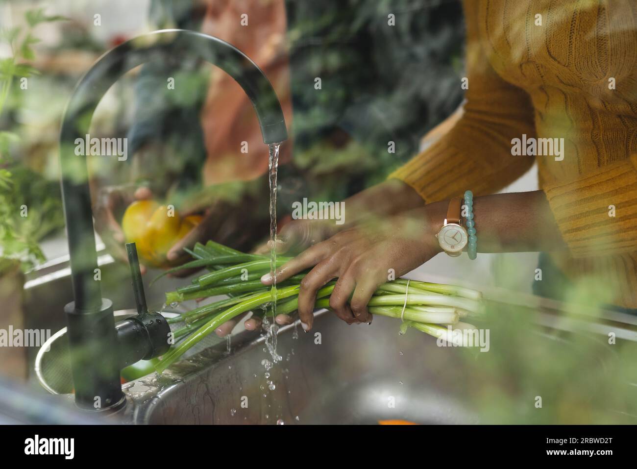 Hands of african american couple rinsing vegetables in kitchen Stock Photo