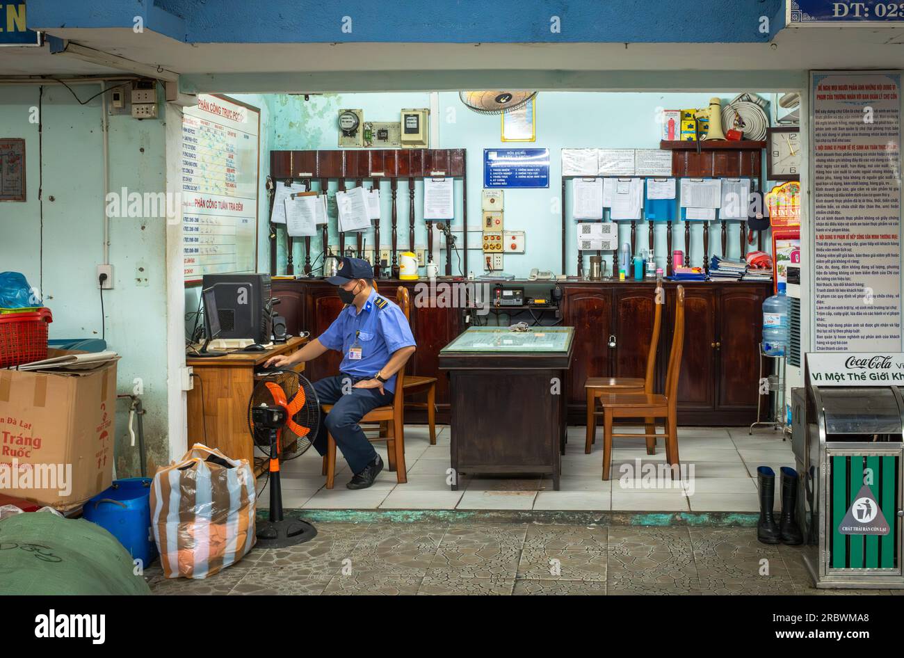 A uniformed security guard at Con Market in Danang, Vietnam, looks at a computer in his office. Stock Photo