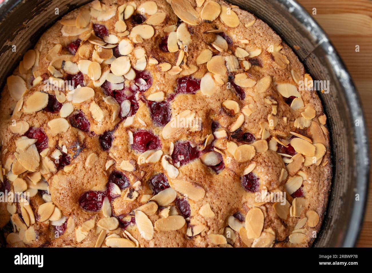 Homemade cherry pie with almonds in a round baking pan on wooden table Stock Photo