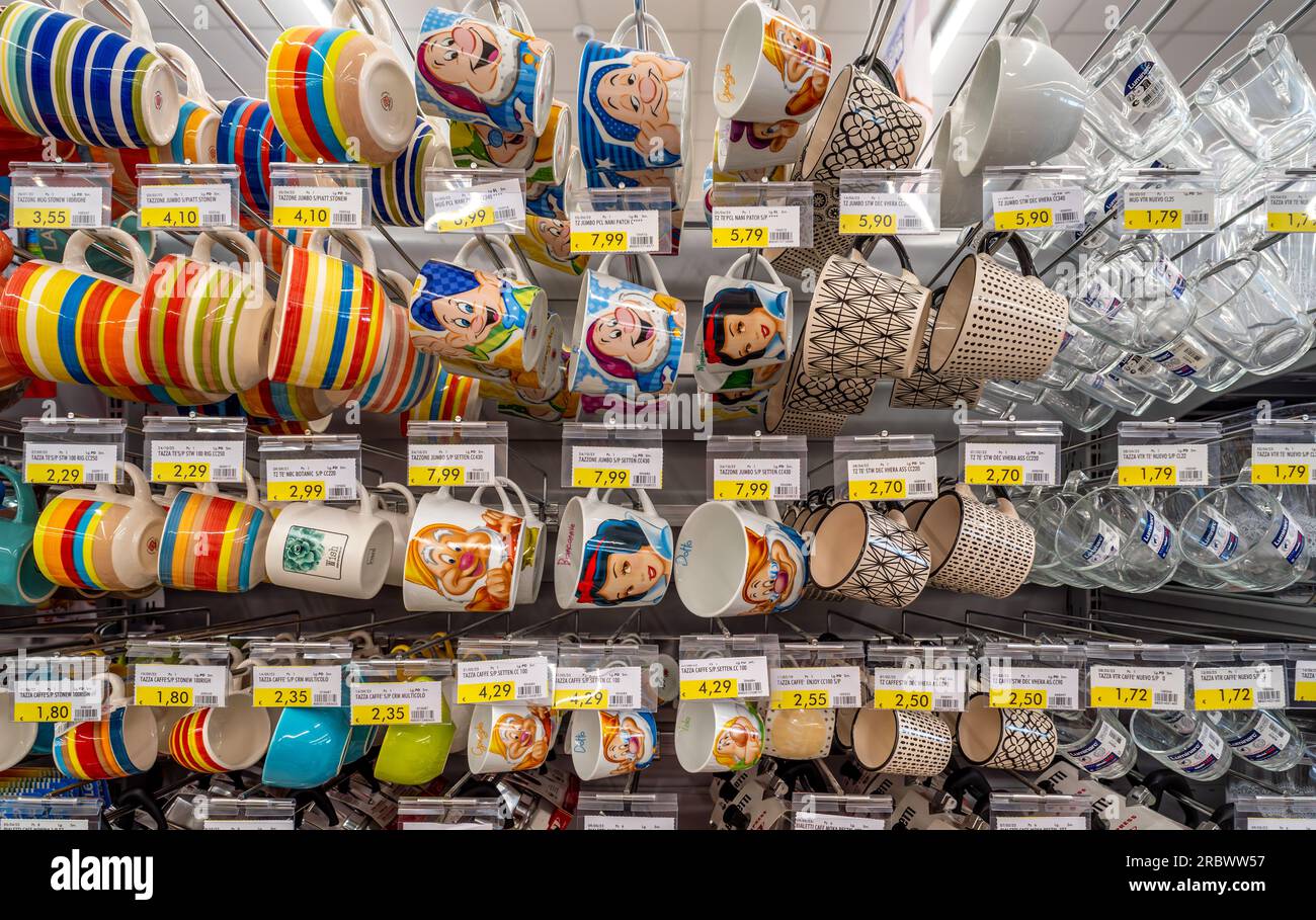 Italy - July 10, 2023: Multi-colored mugs and cups with drawings of the cartoon Snow White and the Seven Dwarfs displayed for sale on the shelf of an Stock Photo