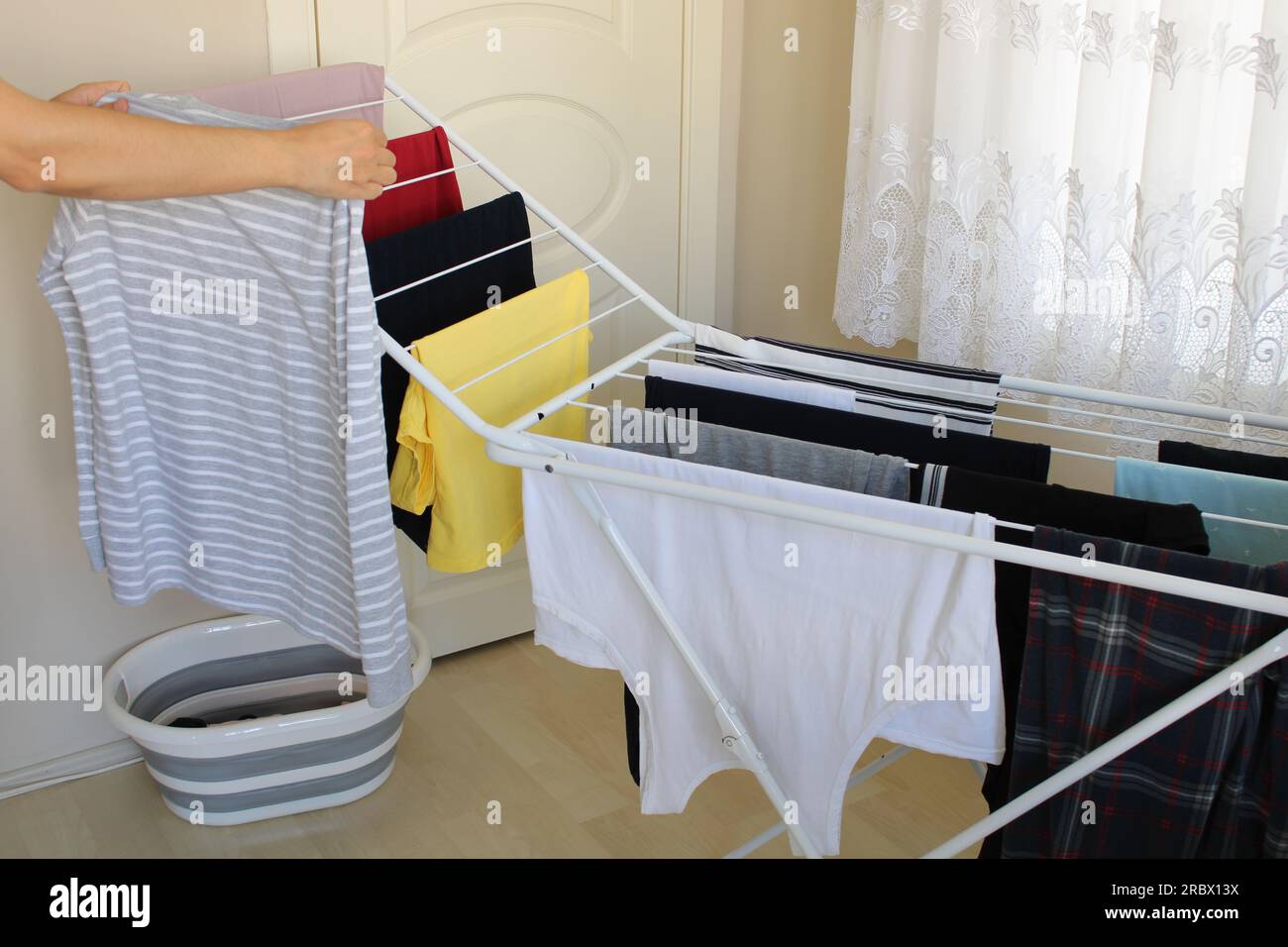 Clean laundry hanging on drying rack in room. Many or lots of washed laundry lined up to be dry. Stock Photo