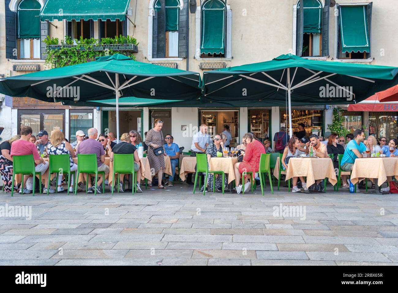 Venice, Italy - May 29 2023: Tourists and locals relaxing at an outdoor cafe resturant in Venice, near St. Mark Square Stock Photo