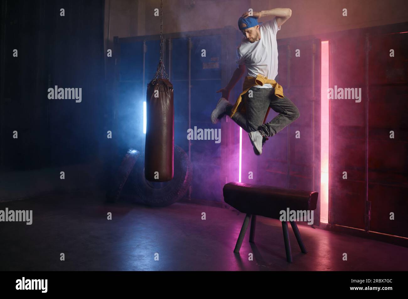 Young adult b-boy breakdancer jumping on air over loft gym background Stock Photo