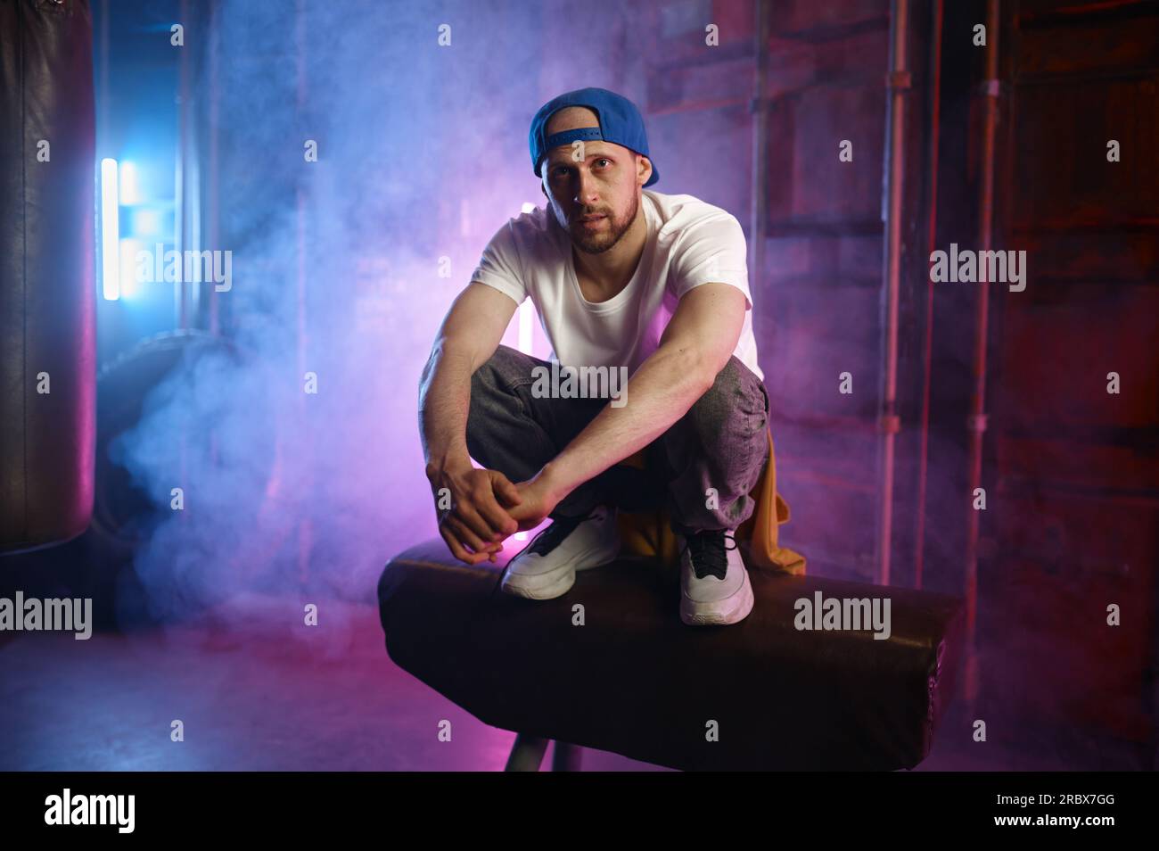 Young adult male hiphop performer breakdancer sitting in stylish street clothes Stock Photo