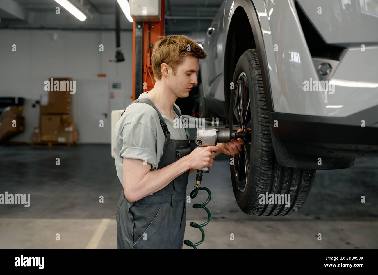 Professional man mechanic changing car wheel using electric drill Stock Photo