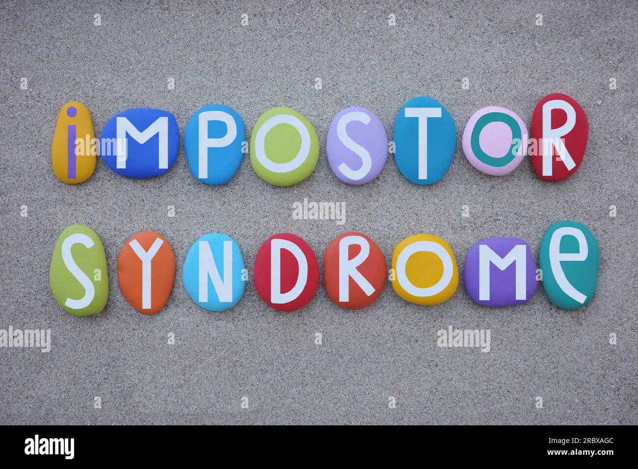 Impostor syndrome, creative text composed with multi colored stone letters over beach sand Stock Photo