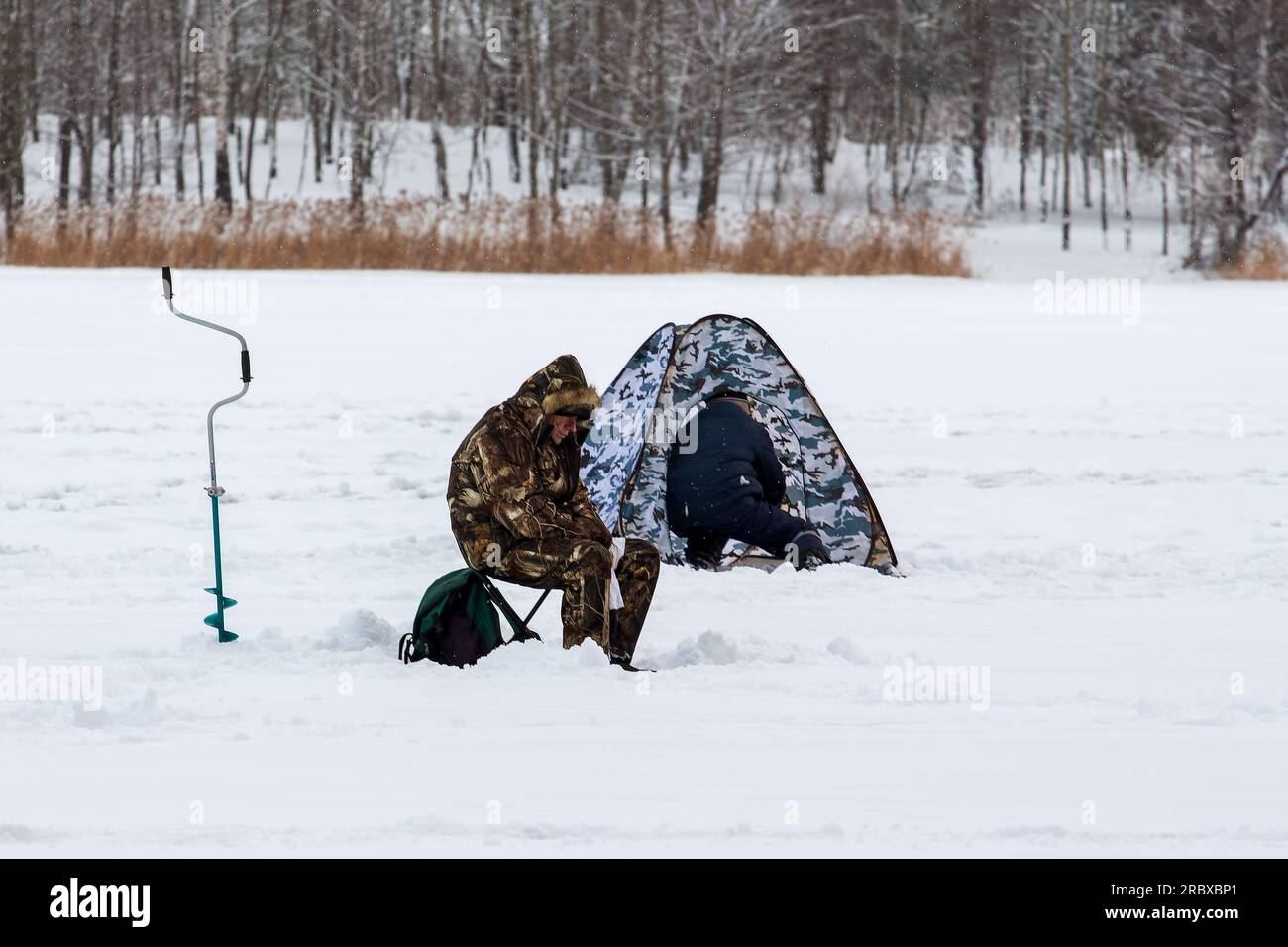 Winter fishing. Fishermen on the ice of the reservoir with a tent and fishing accessories Stock Photo