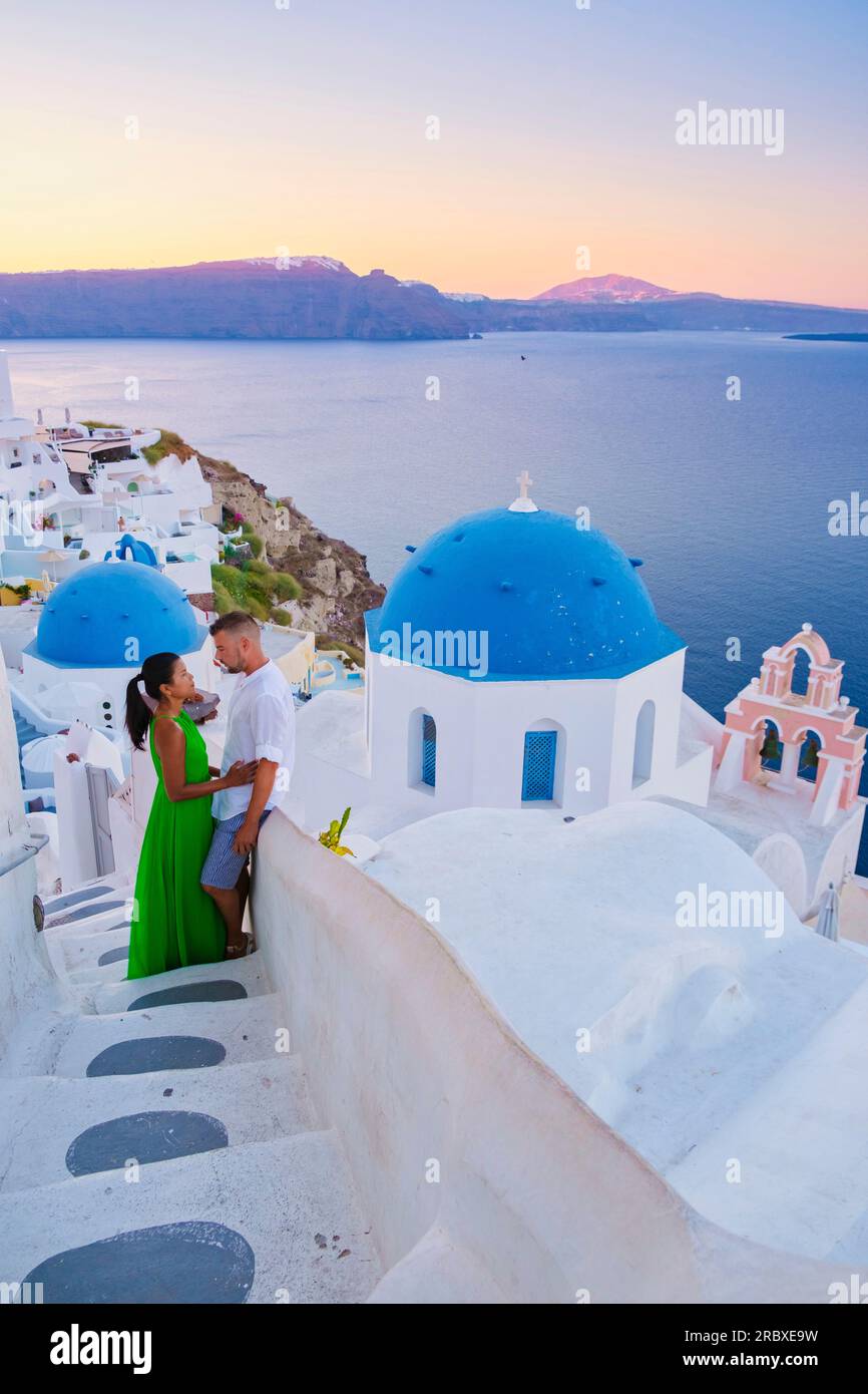 Couple hugging and kissing on a romantic vacation in Santorini Greece, men and women visit the whitewashed Greek village of Oia . Stock Photo