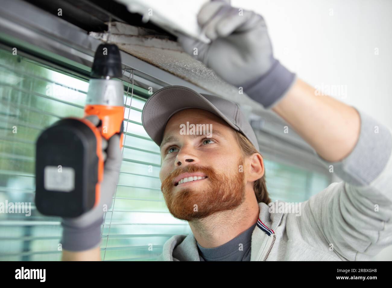 worker drilling ceiling for curtain rail Stock Photo